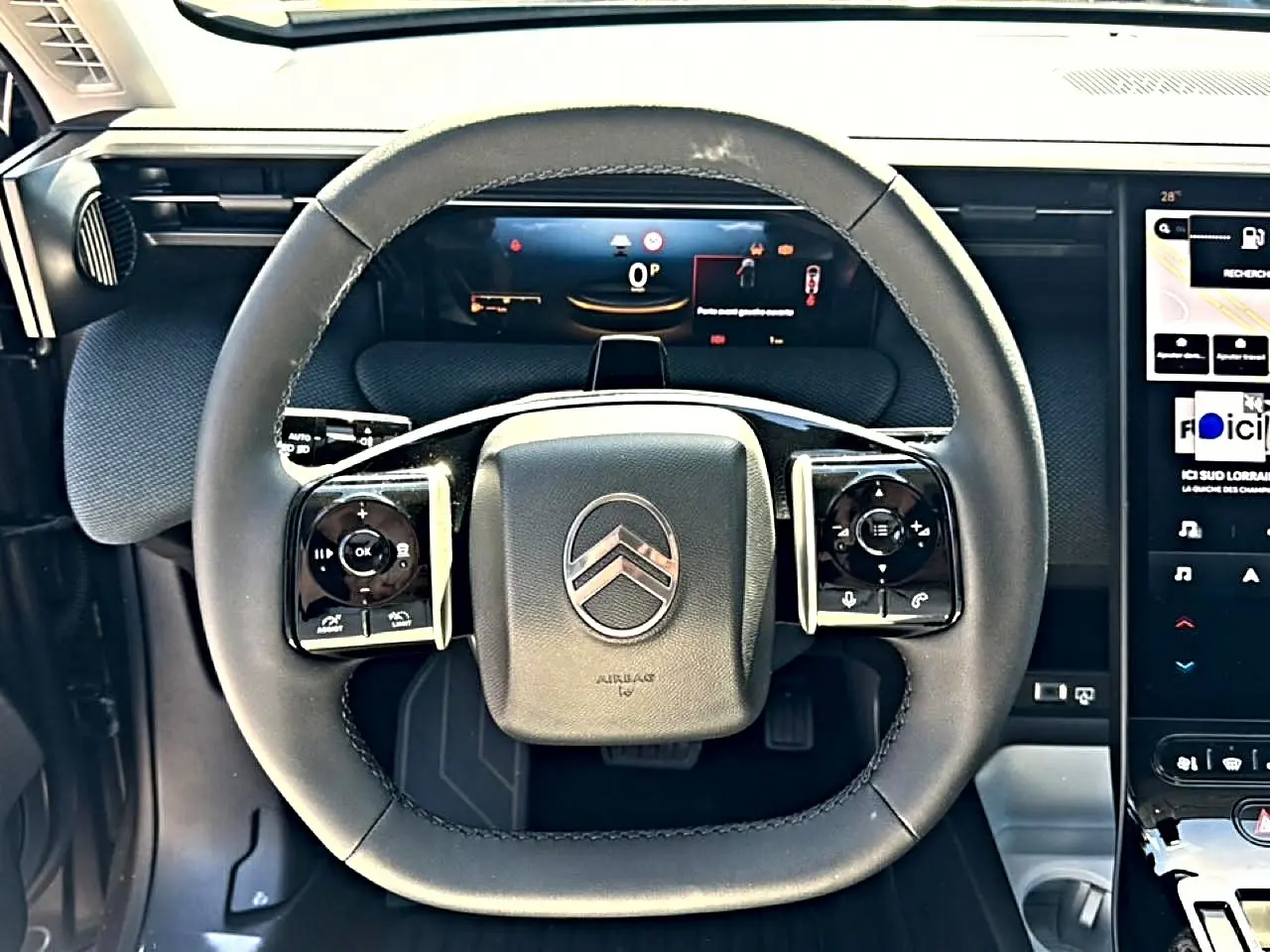 Vue rapprochée du volant multifonction noir du Citroën C5 Aircross 2026 avec tableau de bord numérique et écran tactile.