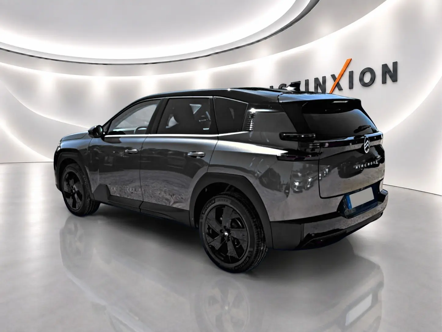 Vue 3/4 arrière droite du Citroën C5 Aircross gris platinium avec toit noir et jantes alliage noires dans un showroom lumineux.