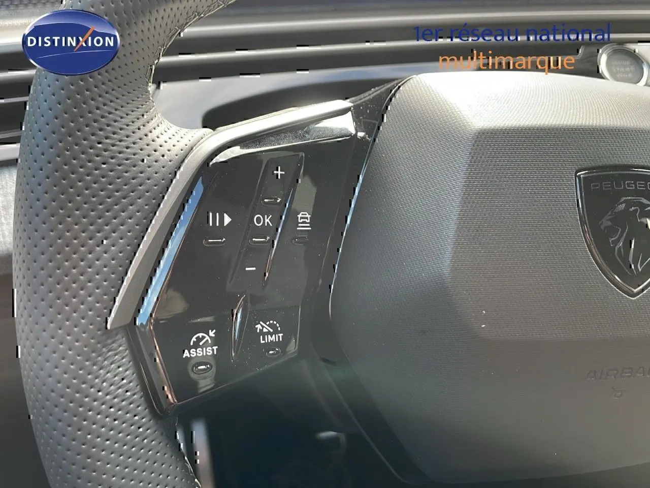 Gros plan sur les commandes multifonctions à gauche du volant perforé du Peugeot 3008 hybride bleu Ingaro métal.