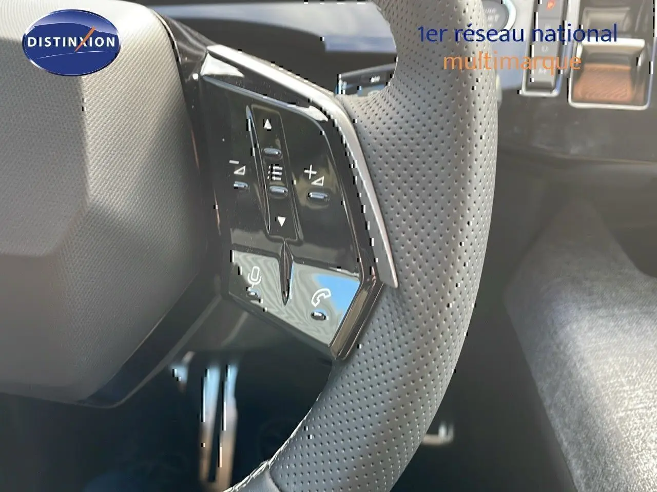 Gros plan sur le volant perforé avec commandes intégrées du Peugeot 3008 hybride bleu Ingaro métal toit noir 2025.