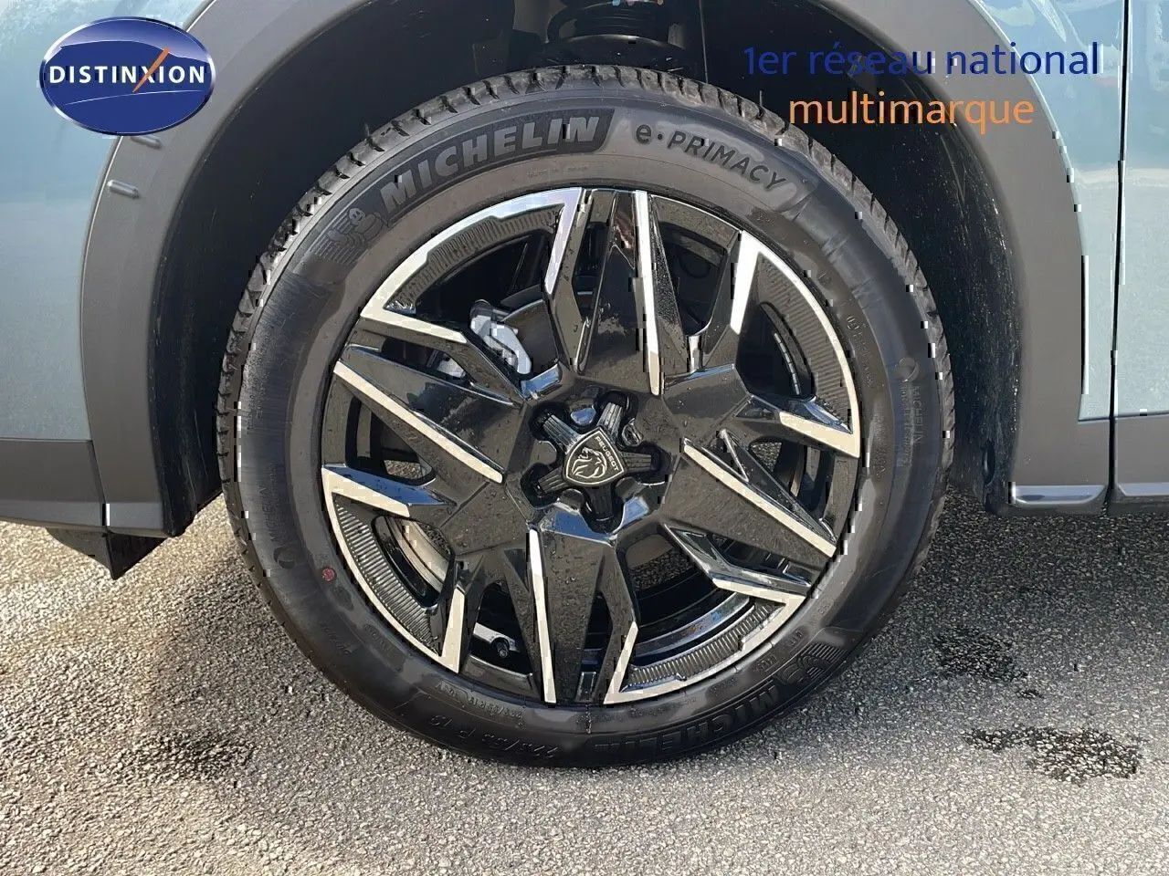 Gros plan sur la roue avant gauche d'un Peugeot 3008 bleu Ingaro métal avec jante alliage noire et argentée.