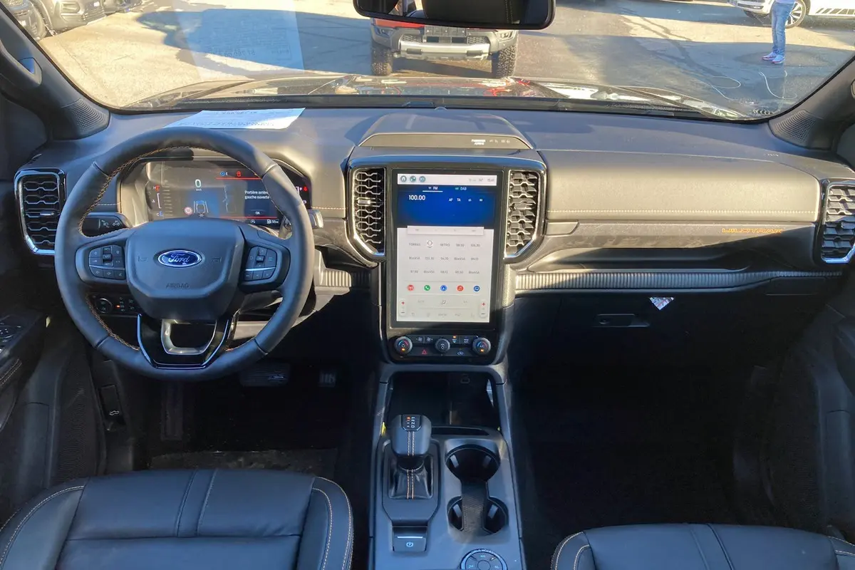 Vue frontale de l'intérieur du Ford Ranger 2025 bleu lightning, tableau de bord avec écran tactile vertical et volant multifonction.