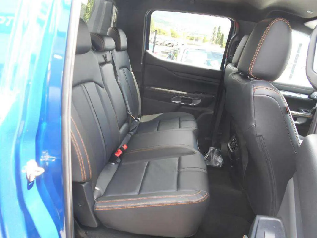Vue intérieure côté gauche des sièges arrière en cuir noir avec surpiqûres orange du Ford Ranger 2025 Bleu Lightning Wildtrak Plus.