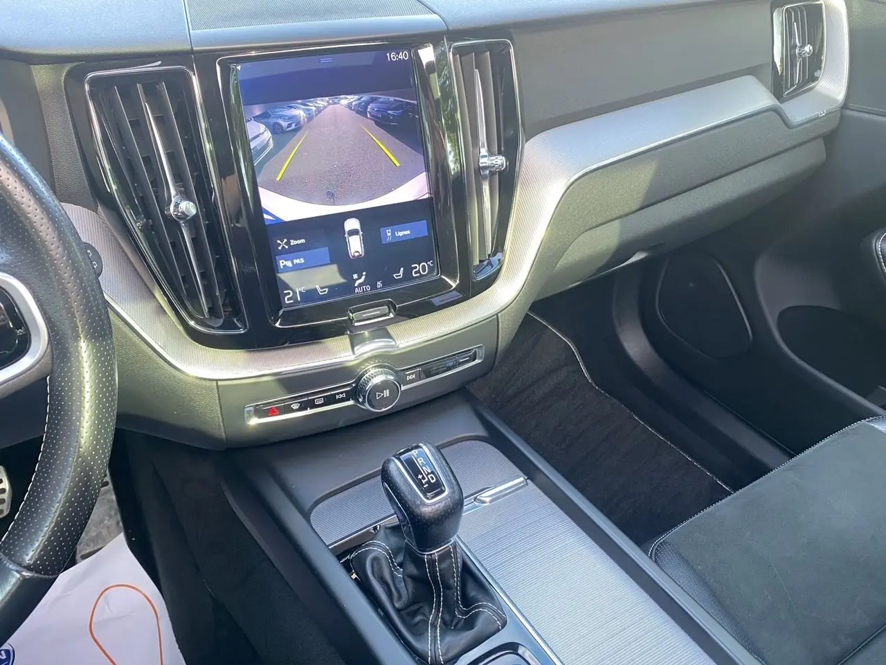 Vue intérieure centrée sur la console centrale et écran tactile affichant la caméra de recul du Volvo XC60 blanc.