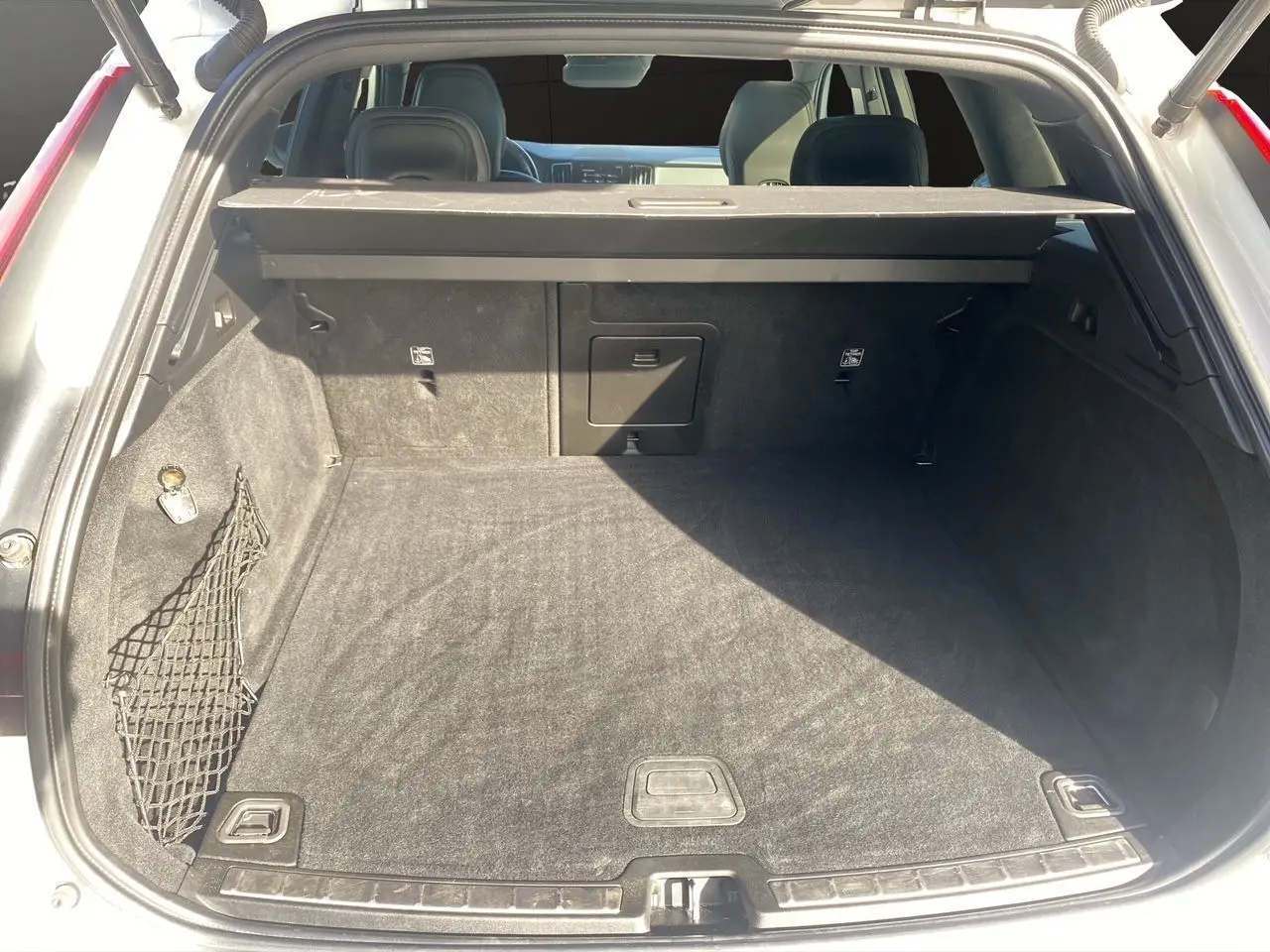 Coffre ouvert d'un Volvo XC60 blanc 2019, vue arrière montrant l'espace de chargement et la plage arrière noire.