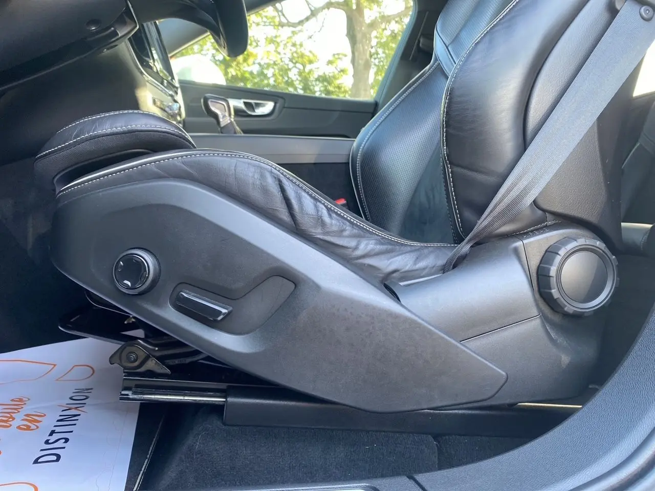 Gros plan sur le siège conducteur en cuir noir avec réglages électriques du Volvo XC60 D4 blanc, intérieur côté gauche.