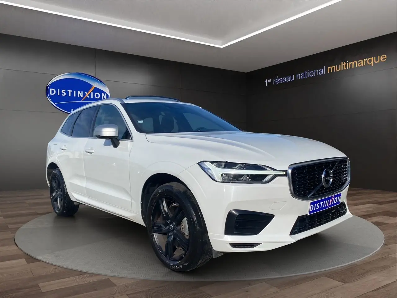 Vue 3/4 avant d'un Volvo XC60 blanc 2019 avec jantes noires et calandre noire R-Design.