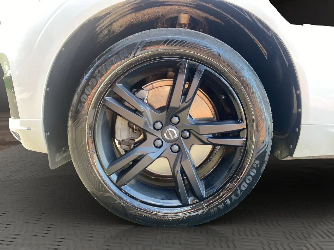 Gros plan sur la roue avant droite noire à jante alliage du Volvo XC60 blanc, version D4 R-Design 2019.