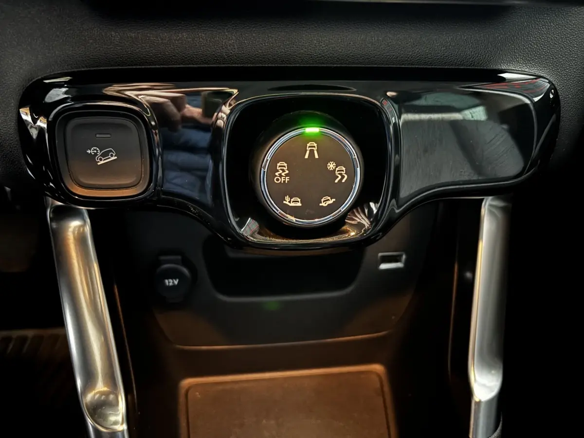 Gros plan sur la molette de sélection des modes de conduite et bouton de régulateur sur la console centrale noire du Citroën C3 Aircross gris clair.