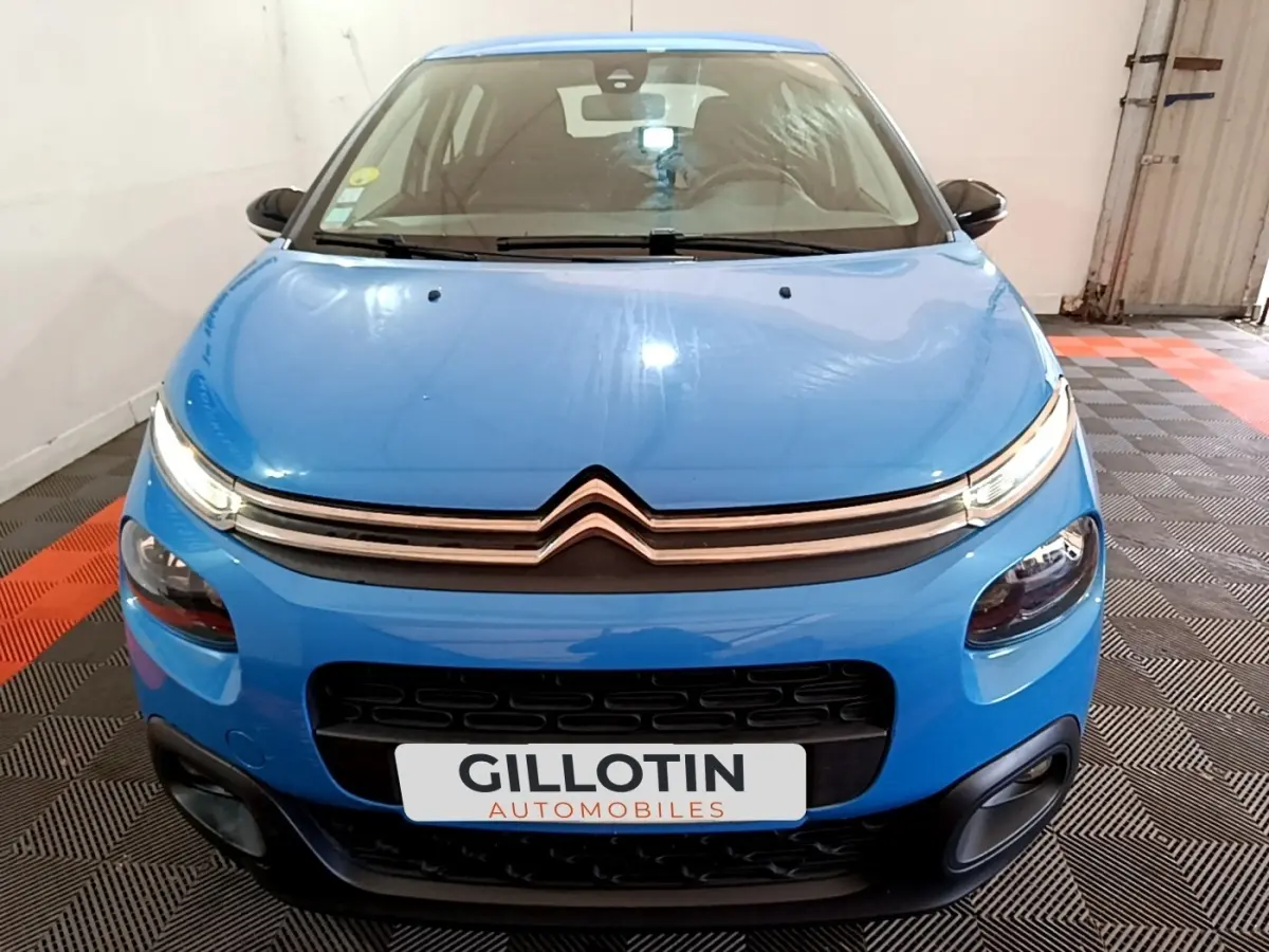 Vue avant d'une Citroën C3 bleu vif avec calandre chromée et phares LED, stationnée sur sol à damier noir et rouge.