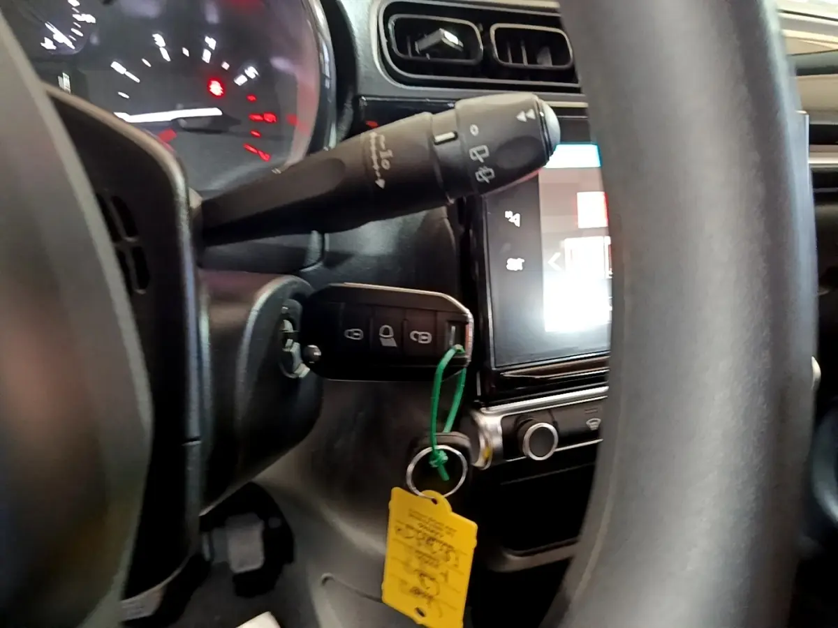 Vue intérieure rapprochée du tableau de bord et du volant d’une Citroën C3 2017 avec clé insérée et écran tactile allumé.