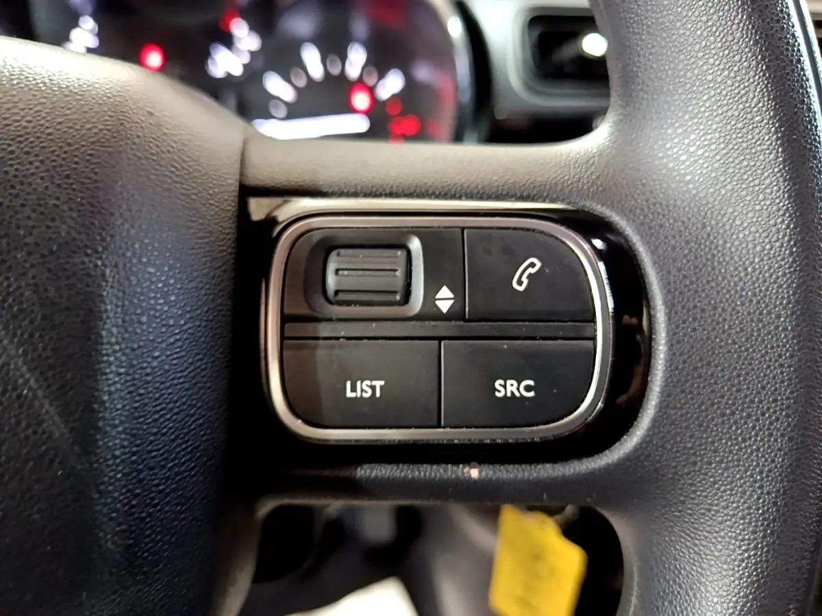 Gros plan sur les commandes multifonctions noires du volant d’une Citroën C3 2017, avec boutons LIST et SRC visibles.