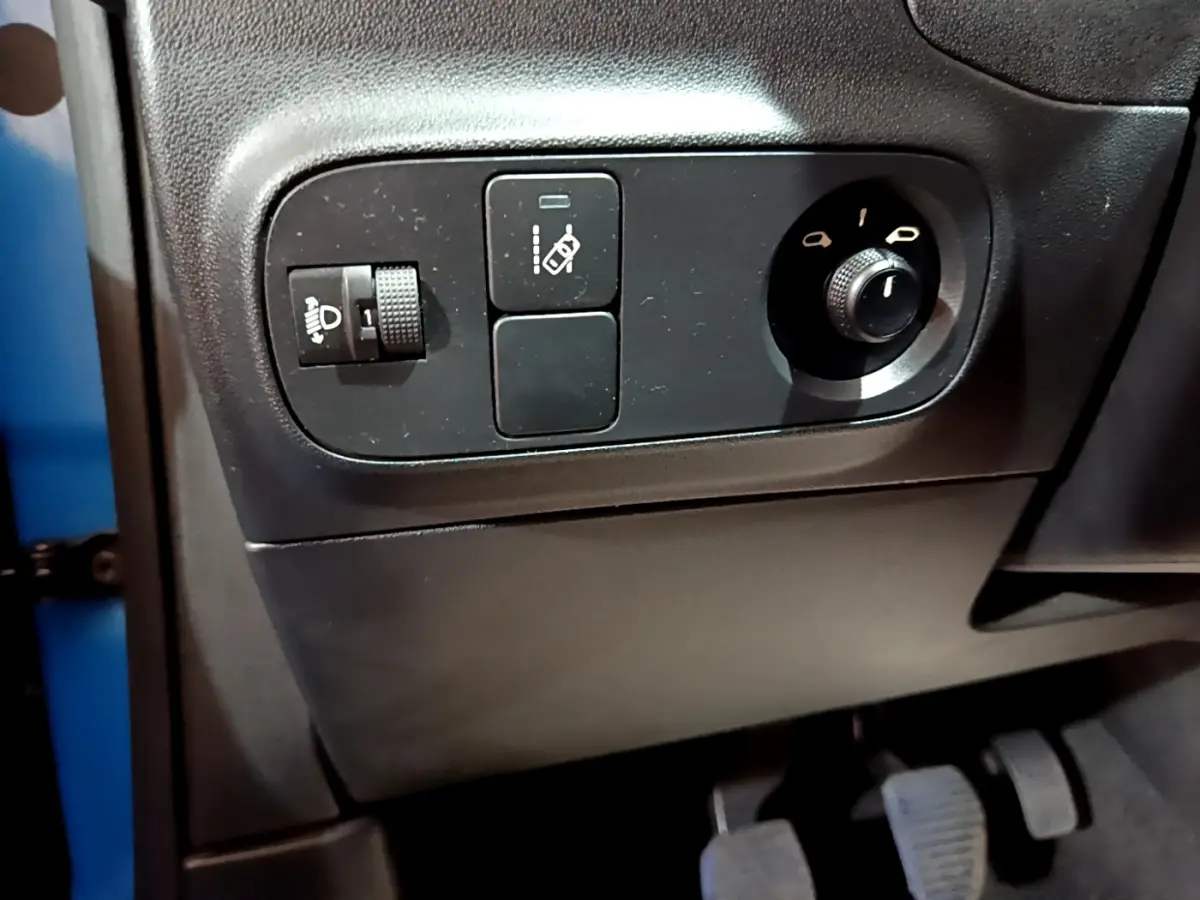 Gros plan sur les commandes côté gauche du tableau de bord d'une Citroën C3 bleue, avec réglage des phares et des rétroviseurs.