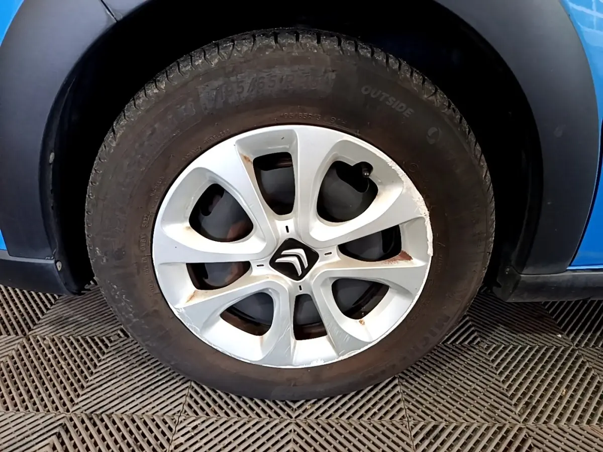 Gros plan sur la roue avant gauche d'une Citroën C3 bleu, avec jante en alliage argentée et logo Citroën central.