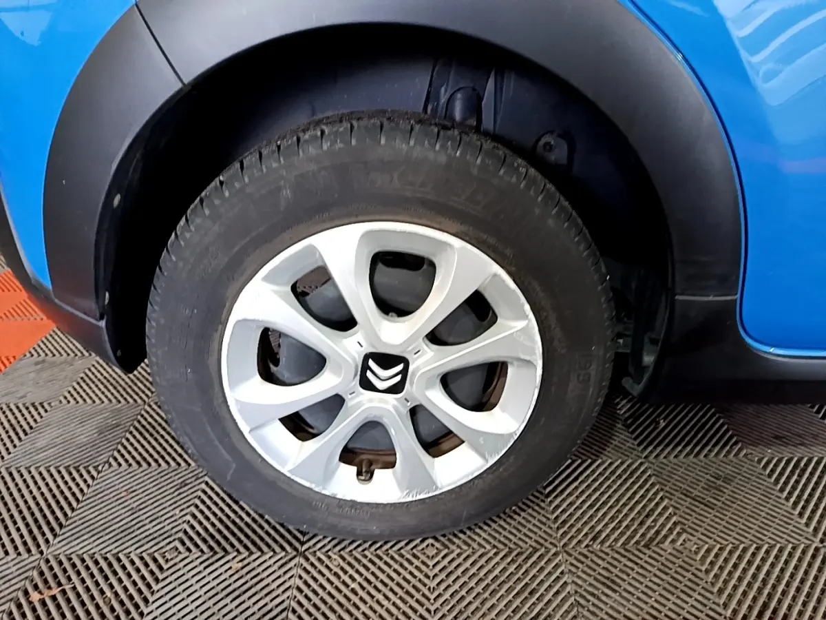 Gros plan sur la roue avant droite d'une Citroën C3 bleu avec jante argentée et logo Citroën central.