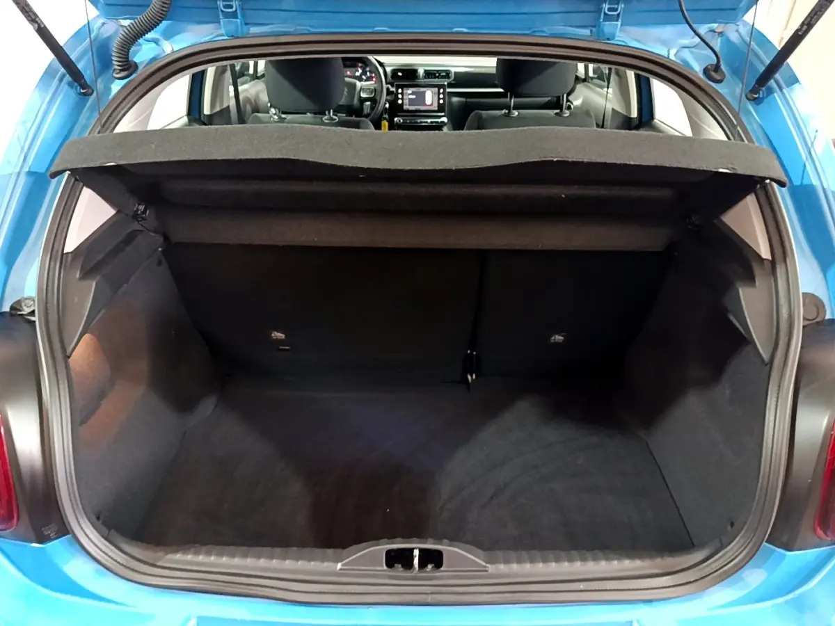 Coffre ouvert d'une Citroën C3 bleu, vue arrière montrant l'intérieur spacieux et la tablette cache-bagages relevée.