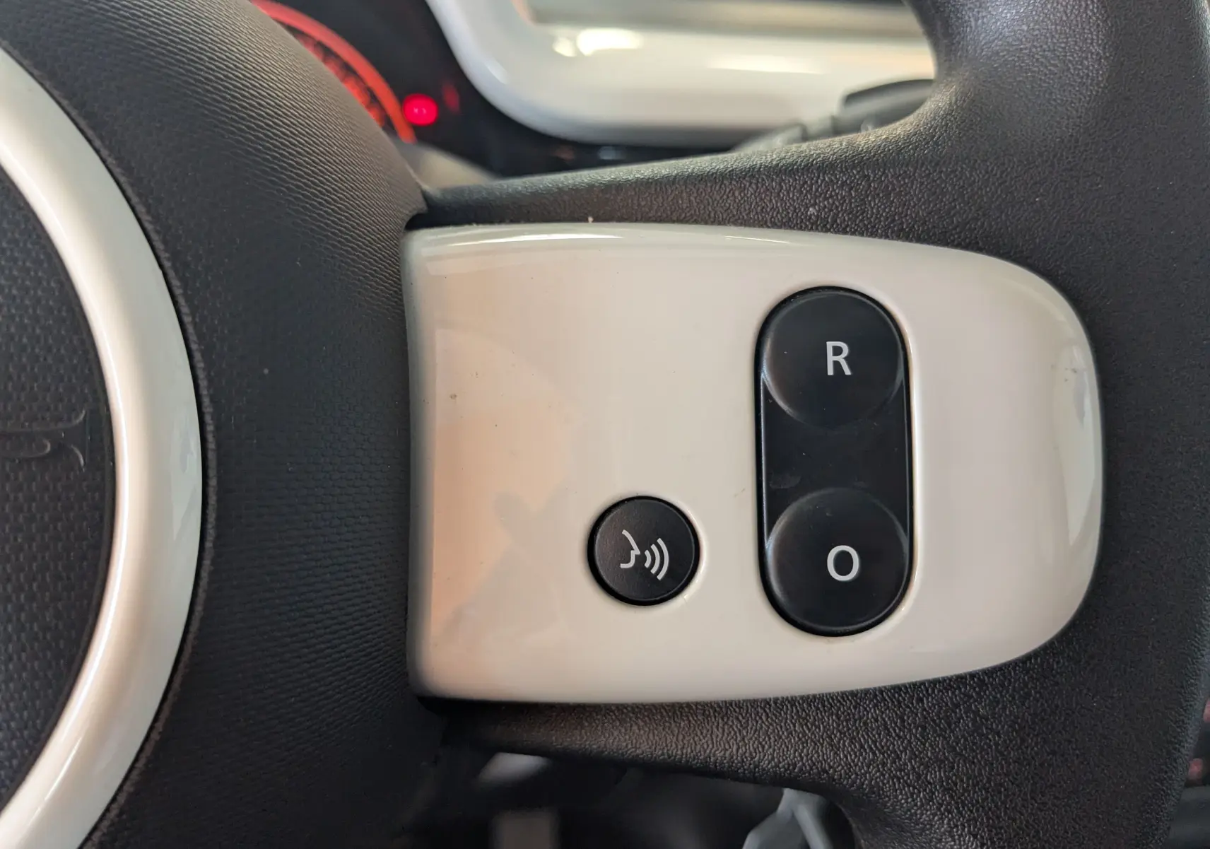 Gros plan sur les commandes grises du volant de la Renault Twingo III 1.0 SCE 65 Limited, boutons R et O visibles.