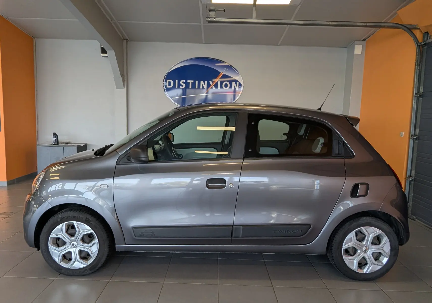 Profil droit d'une Renault Twingo III gris cassiopée, compacte à cinq portes avec jantes originales et rétroviseurs noirs.