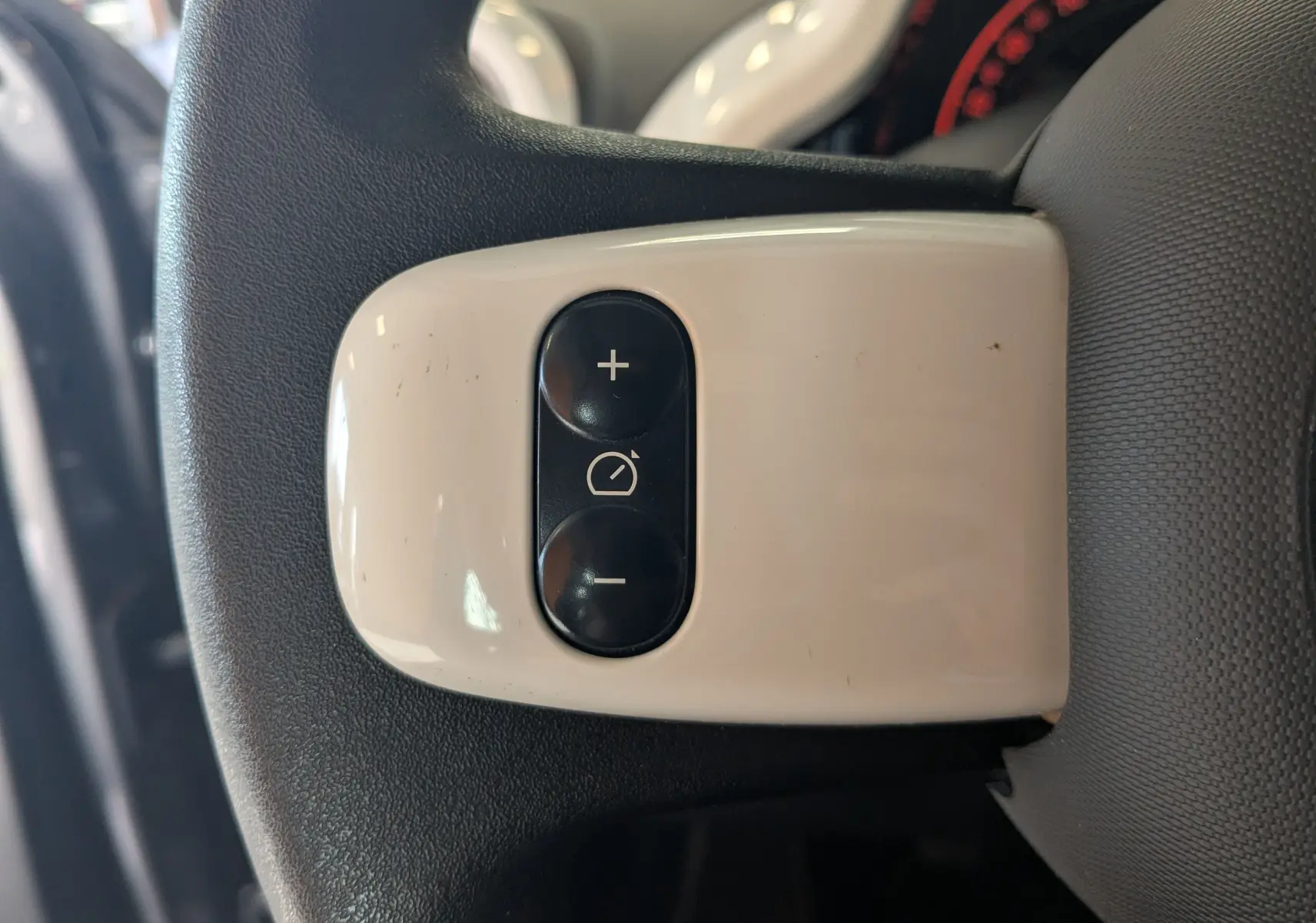 Gros plan sur les boutons de réglage du régulateur de vitesse sur le volant de la Renault Twingo III gris cassiopée.