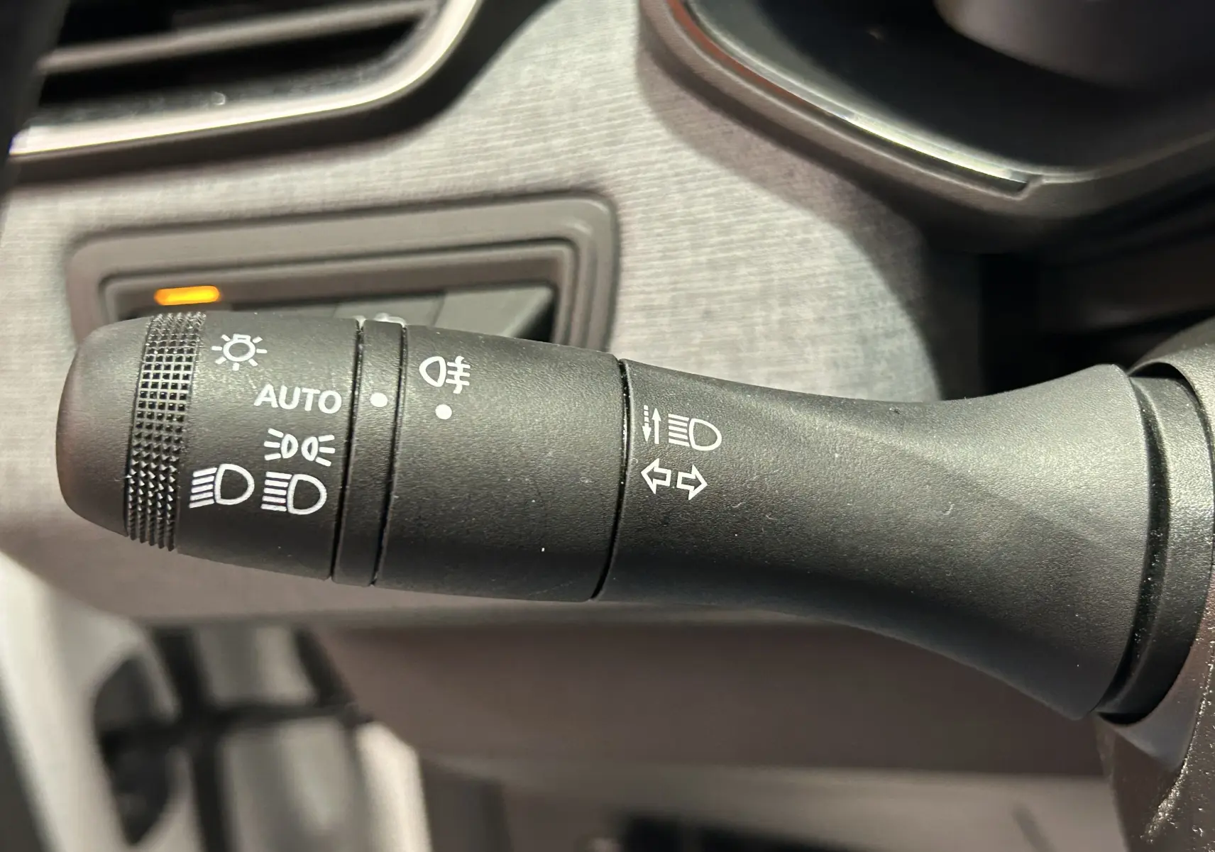 Gros plan sur la commande noire des feux et clignotants dans l’habitacle d’une Renault Clio V 2025.
