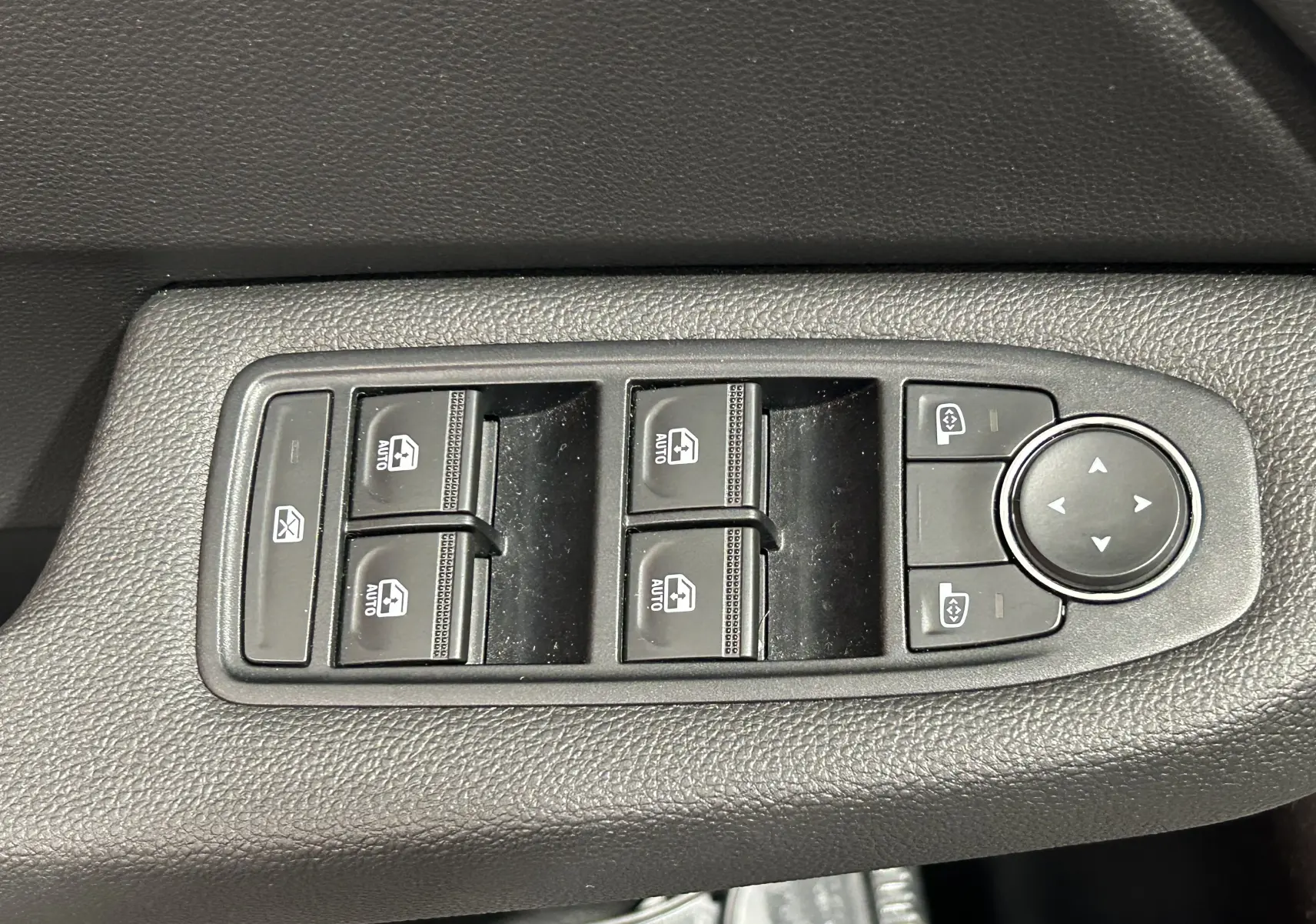 Panneau de commandes des vitres électriques et réglages des rétroviseurs sur la portière intérieure d'une Renault Clio V noire.