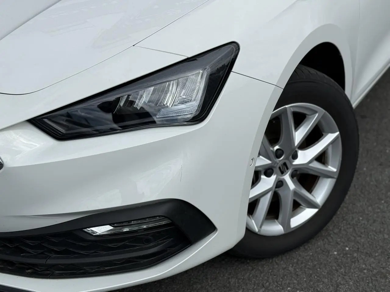 Gros plan sur l'avant droit blanc d'une SEAT LEON 2025, mettant en valeur le projecteur LED et la jante alliage 16 pouces.