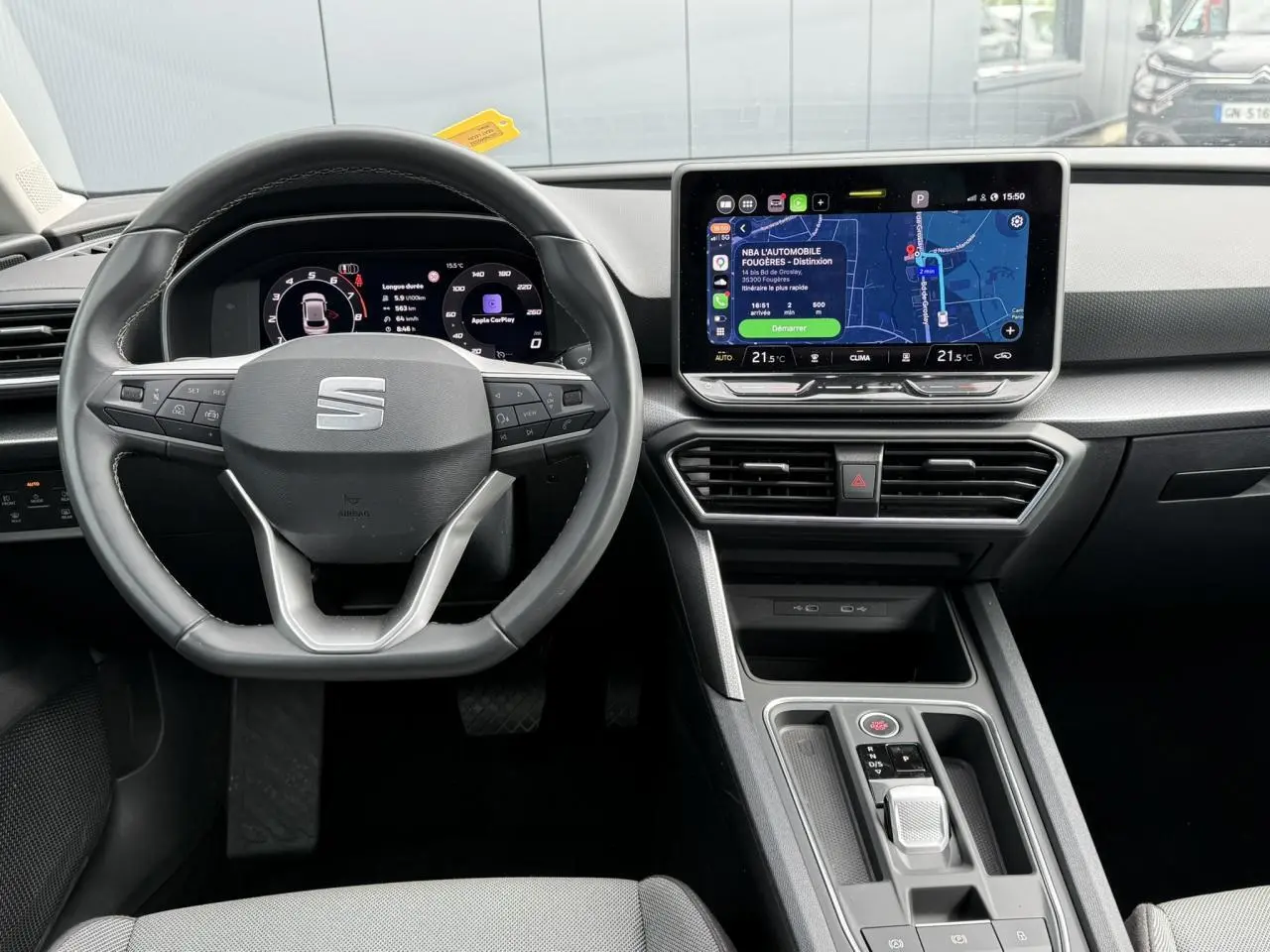 Vue intérieure frontale du poste de conduite de la SEAT LEON 2025 avec volant multifonction et écran tactile central allumé.