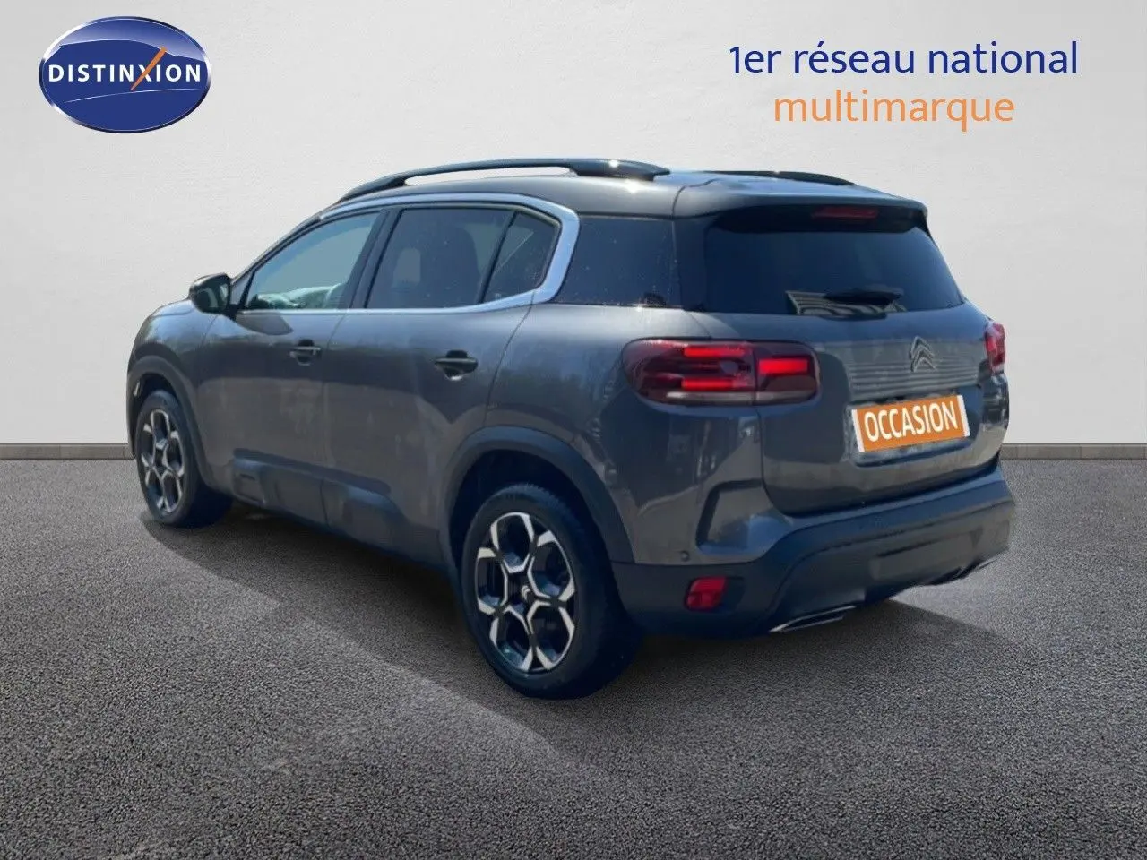 Vue 3/4 arrière gauche d'un Citroën C5 Aircross gris platinium métallisé avec jantes bi-ton et toit noir.