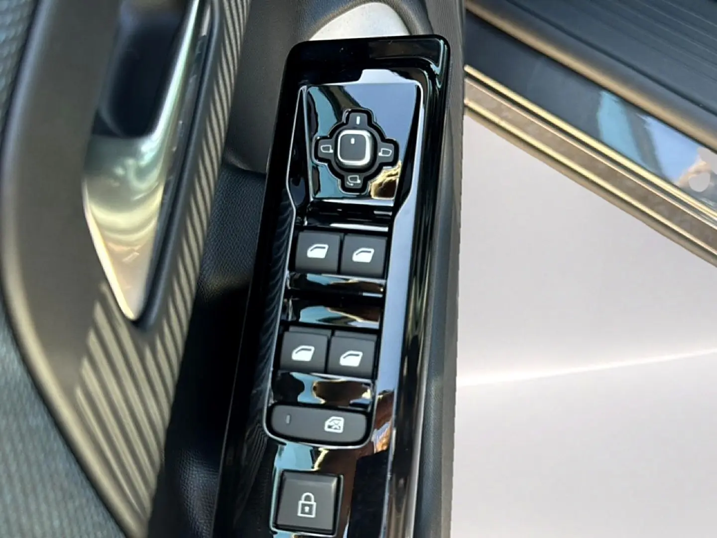 Vue rapprochée du panneau de commandes des vitres côté conducteur d’un Citroën C5 Aircross gris platinium avec insert noir brillant.