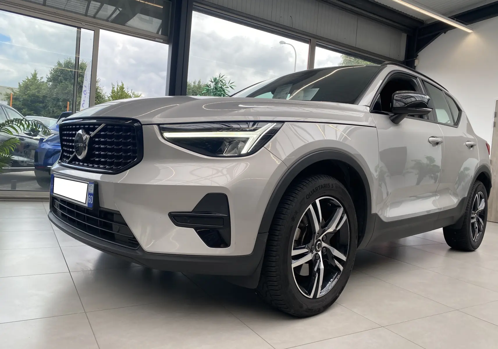 Volvo XC40 B3 163ch Plus DCT 7 argent aurore métallisé vu en 3/4 avant droit, avec calandre noire et jantes alliage bicolores.