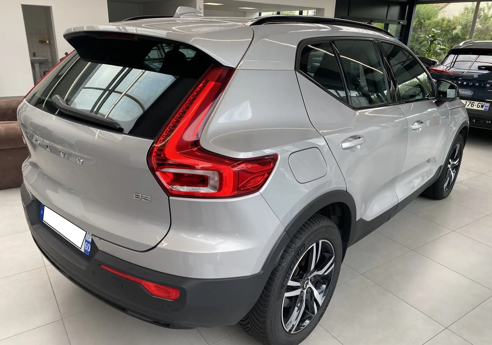Vue 3/4 arrière droite d'un Volvo XC40 B3 argent aurore métallisé avec feux LED et jantes alliage en showroom.
