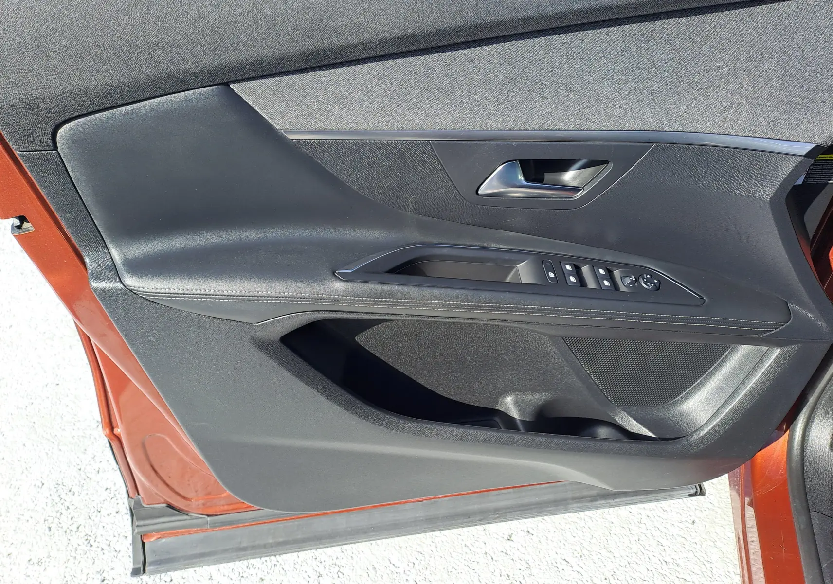 Gros plan sur la porte avant gauche métallique copper du Peugeot 3008 2019 avec commandes de vitres et poignée intégrée.