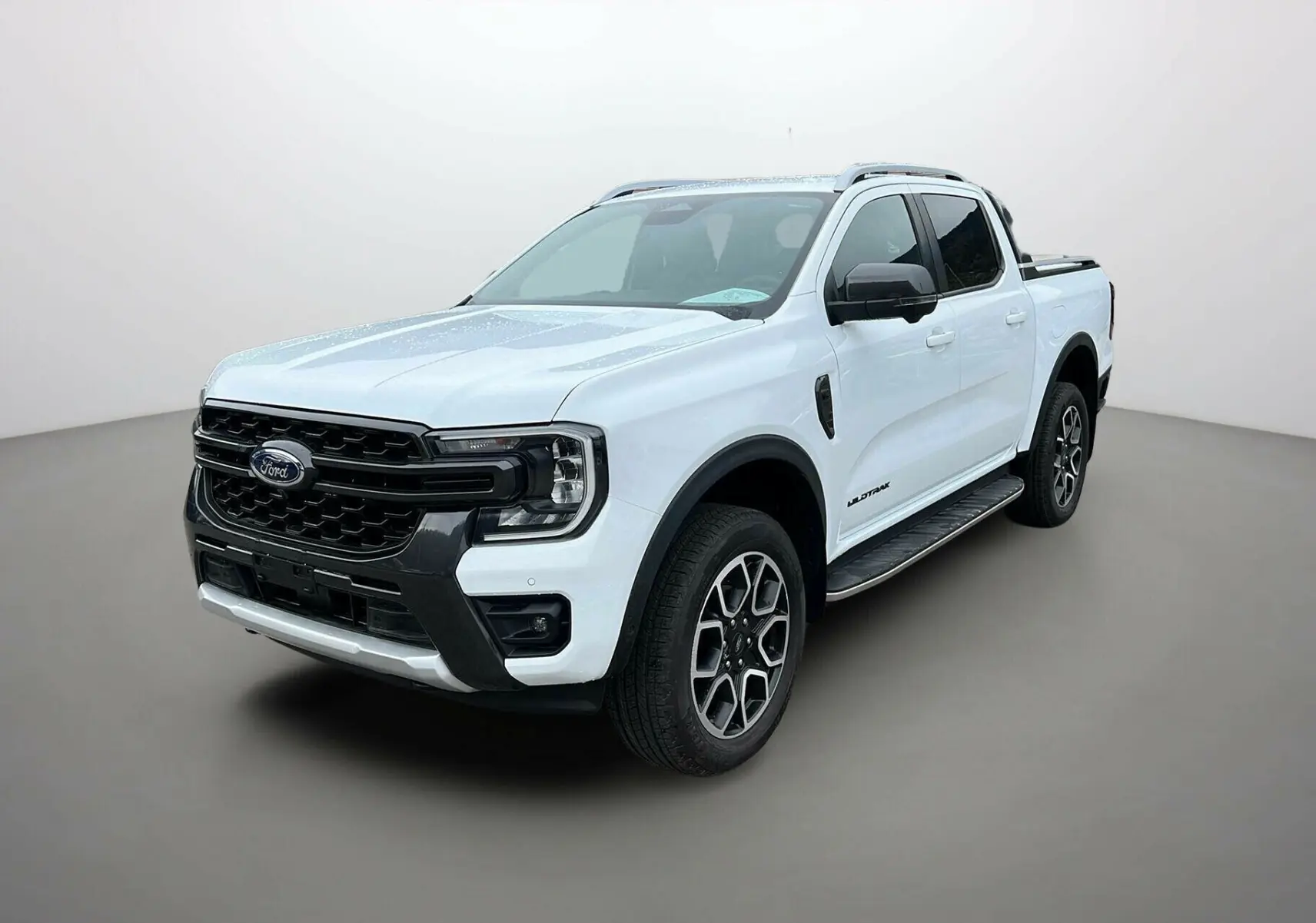 Ford Ranger 2025 blanc glacier en 3/4 avant droit avec calandre noire et jantes alliage distinctives Wildtrak Plus
