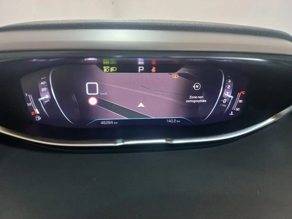Vue rapprochée du tableau de bord numérique du Peugeot 3008 gris clair, affichant la navigation et les compteurs.