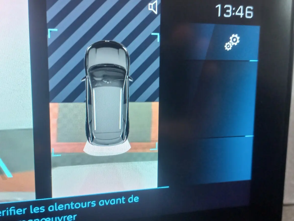 Affichage écran tactile montrant vue aérienne du Peugeot 3008 gris clair en aide au stationnement arrière.