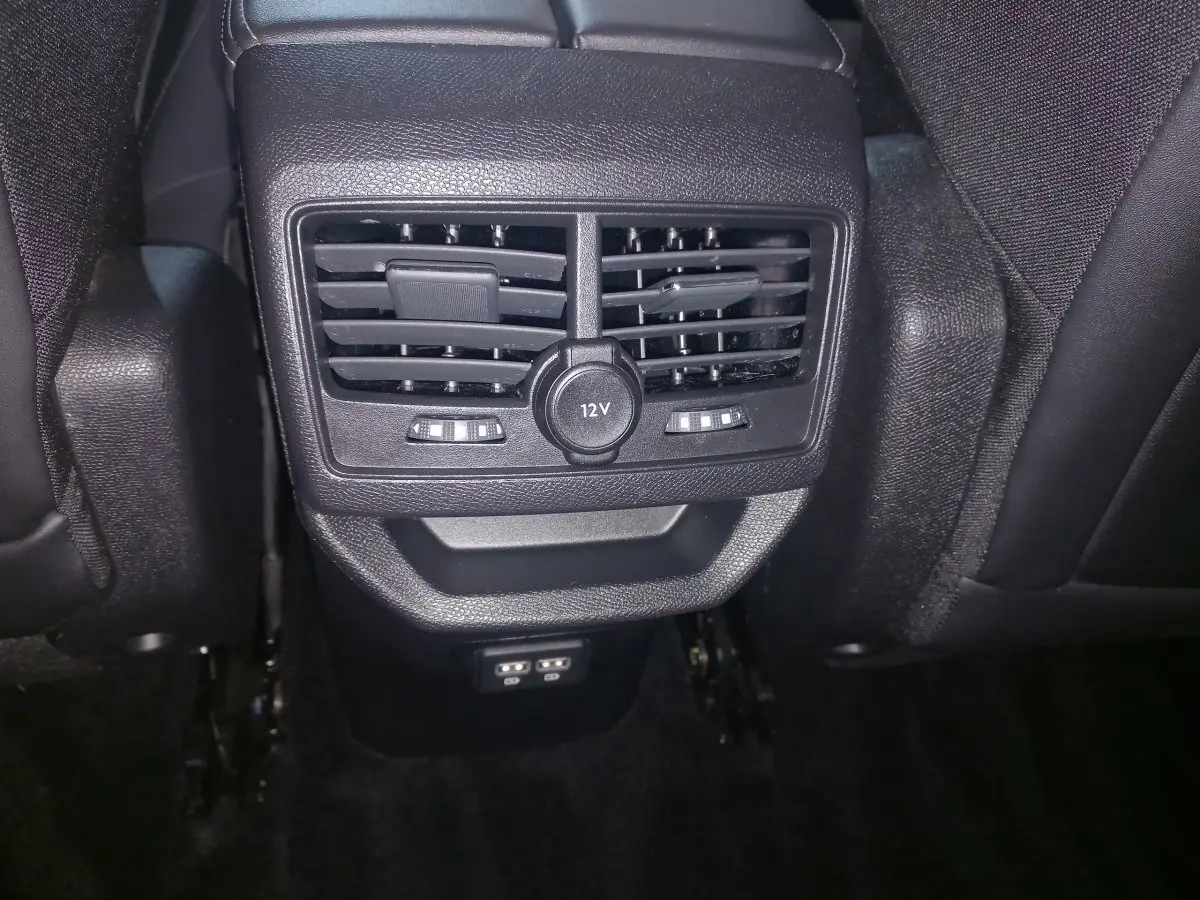 Vue rapprochée des aérateurs arrière et prise 12V du Peugeot 3008 gris clair, entre les sièges arrière en cuir noir.