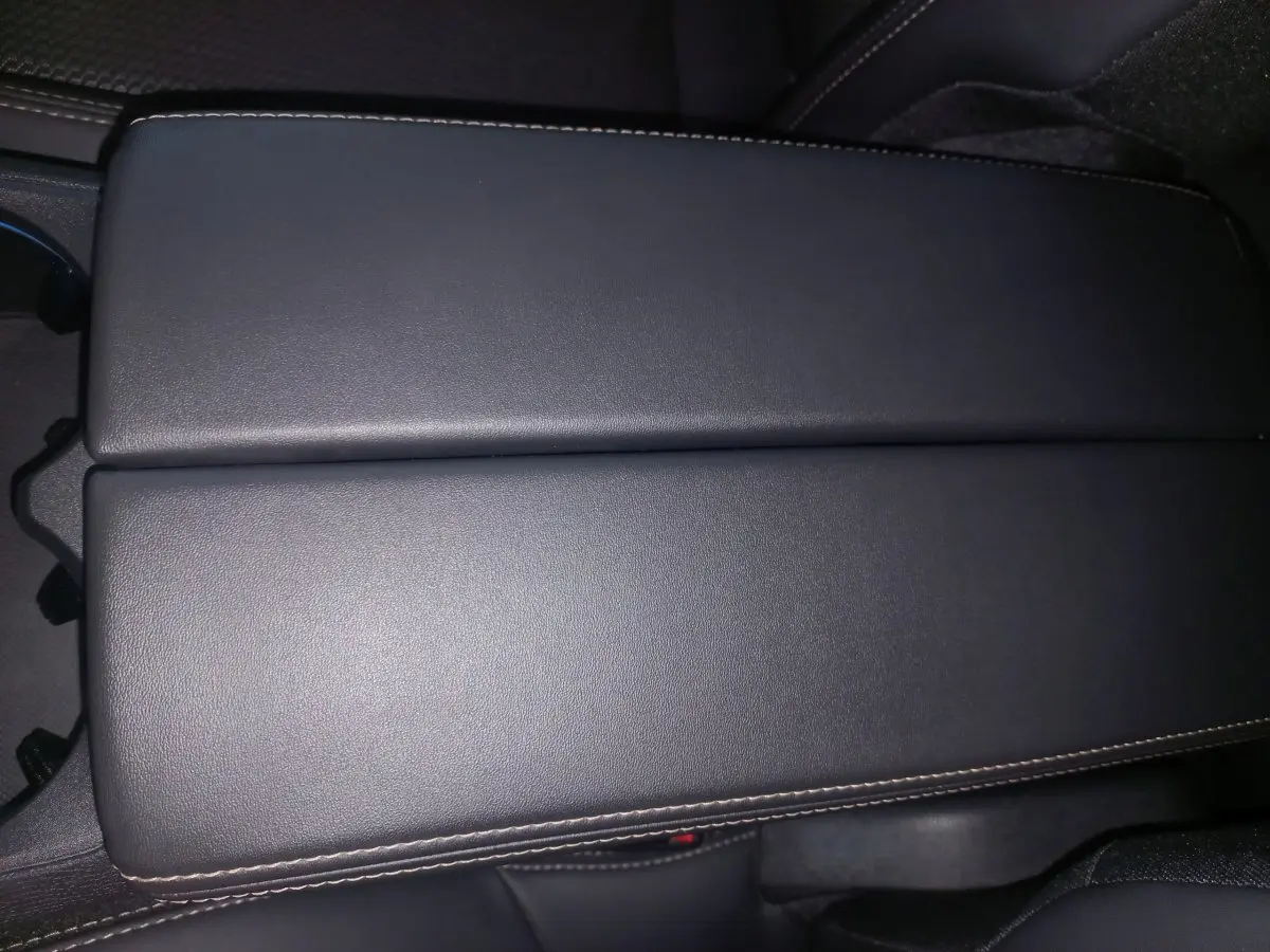 Gros plan sur l'accoudoir central en cuir noir avec surpiqûres contrastées dans l'habitacle du Peugeot 3008 gris clair.