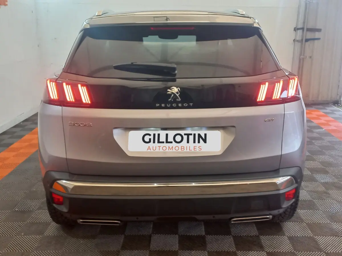 Vue arrière d’un Peugeot 3008 gris clair 2022 avec feux LED allumés et badge GT visible.