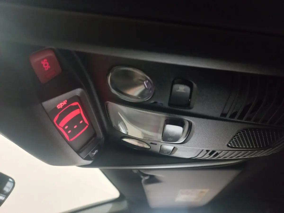 Vue intérieure en gros plan du plafonnier avec commandes d’éclairage et bouton SOS rouge du Peugeot 3008 gris clair 2022.