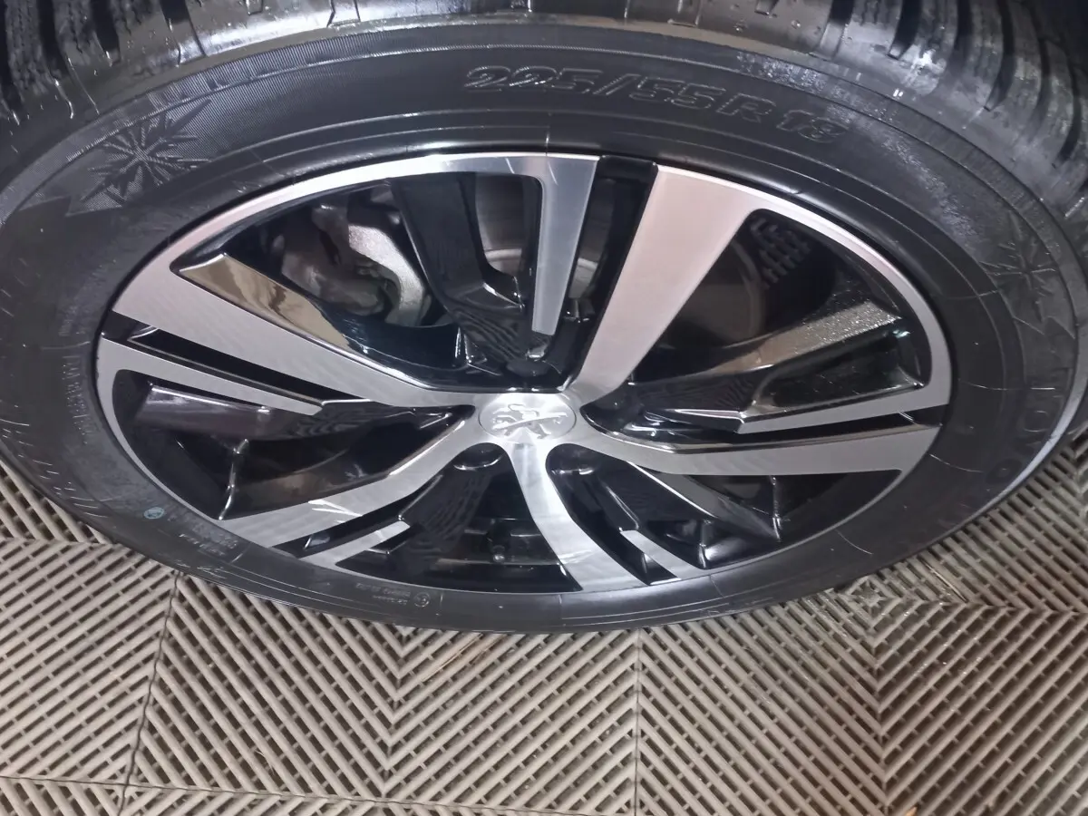 Gros plan sur la jante alliage bicolore noir et argentée du Peugeot 3008 gris clair, mettant en valeur le logo central.