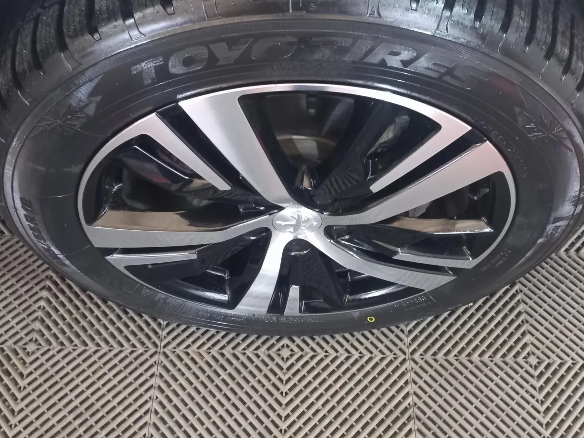 Gros plan sur la jante alliage bicolore noir et argent d’un Peugeot 3008 gris clair, pneu Toyo visible.
