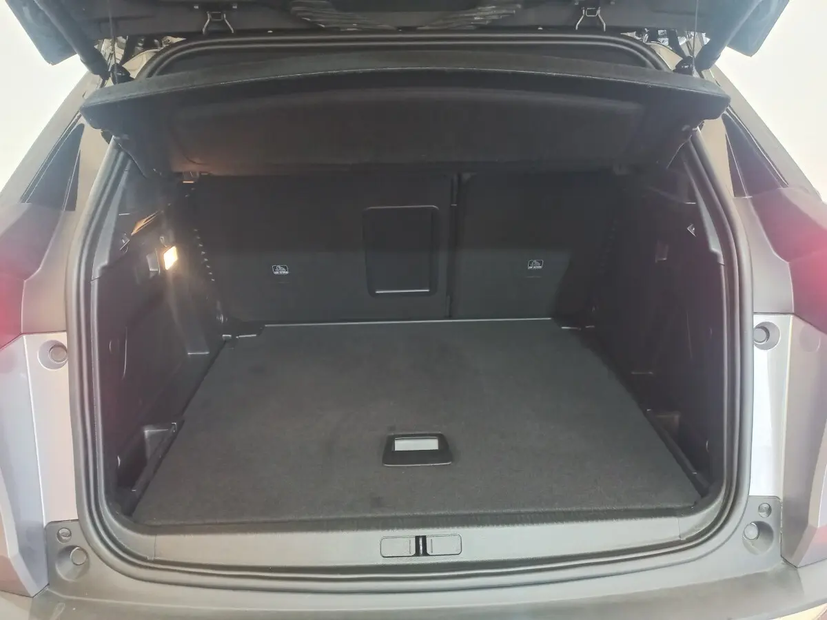 Coffre ouvert vu de l'arrière d'un Peugeot 3008 gris clair, montrant un espace de chargement propre et spacieux.