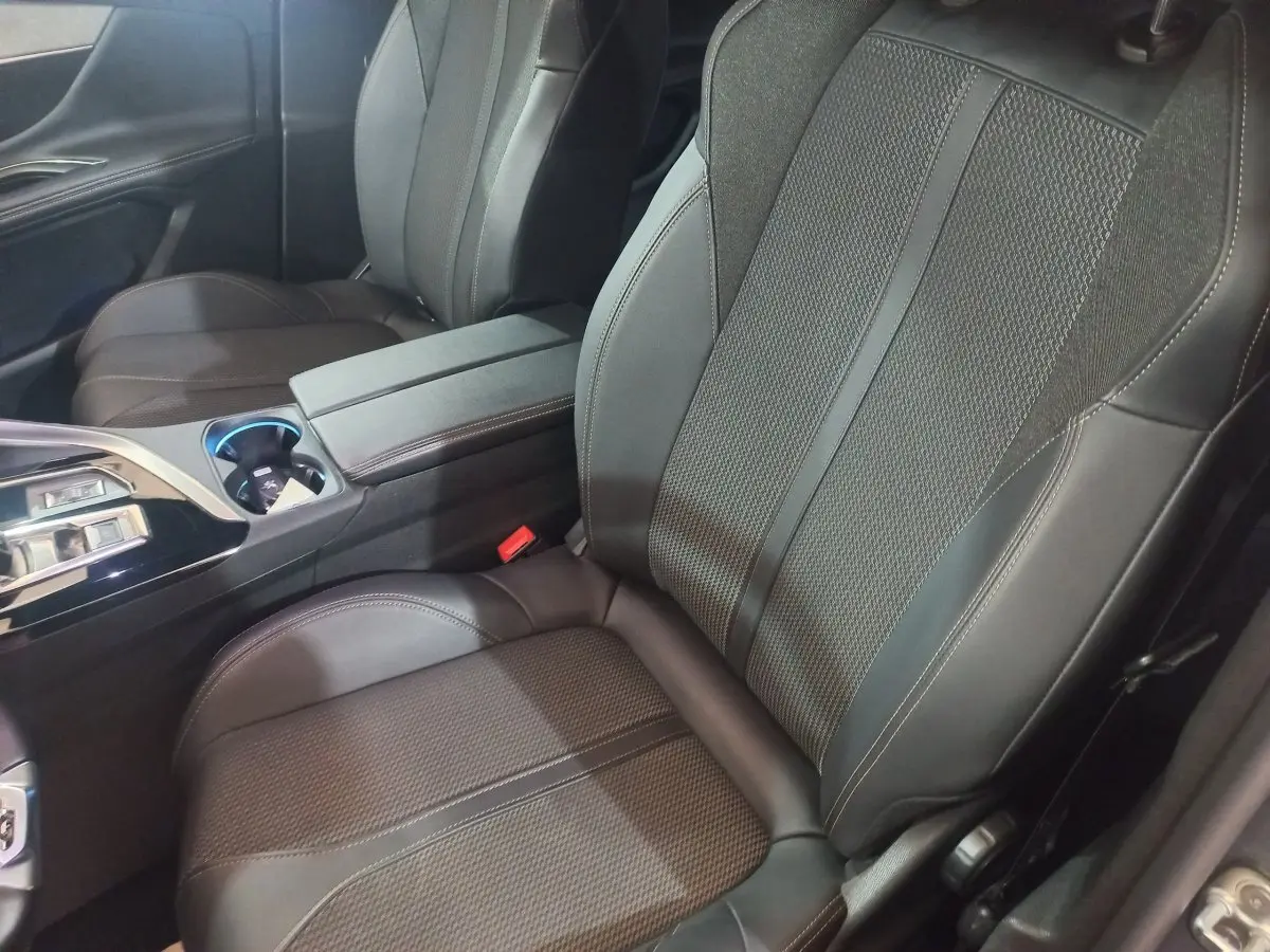 Vue rapprochée des sièges avant en cuir noir du Peugeot 3008 GT 2022, avec console centrale et accoudoir.