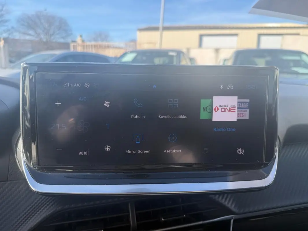 Écran tactile du tableau de bord du Peugeot 208 Hybrid blanc, affichant les réglages climatisation et multimédia.