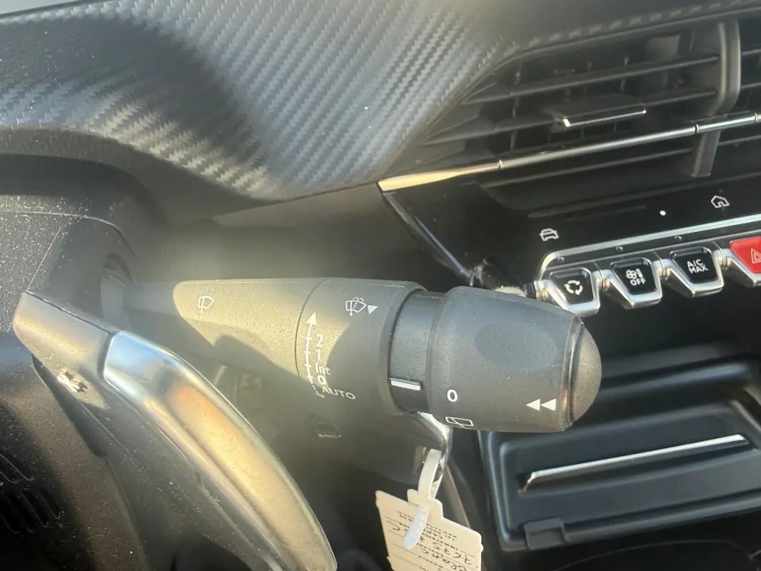 Gros plan sur la commande d’essuie-glace côté gauche du tableau de bord d’une Peugeot 208 Hybrid 110 e-DCS6 Allure blanche 2024.