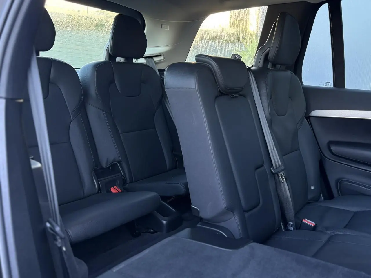 Intérieur du Volvo XC90 T8 2024, vue latérale des sièges arrière en cuir noir sur trois rangées.