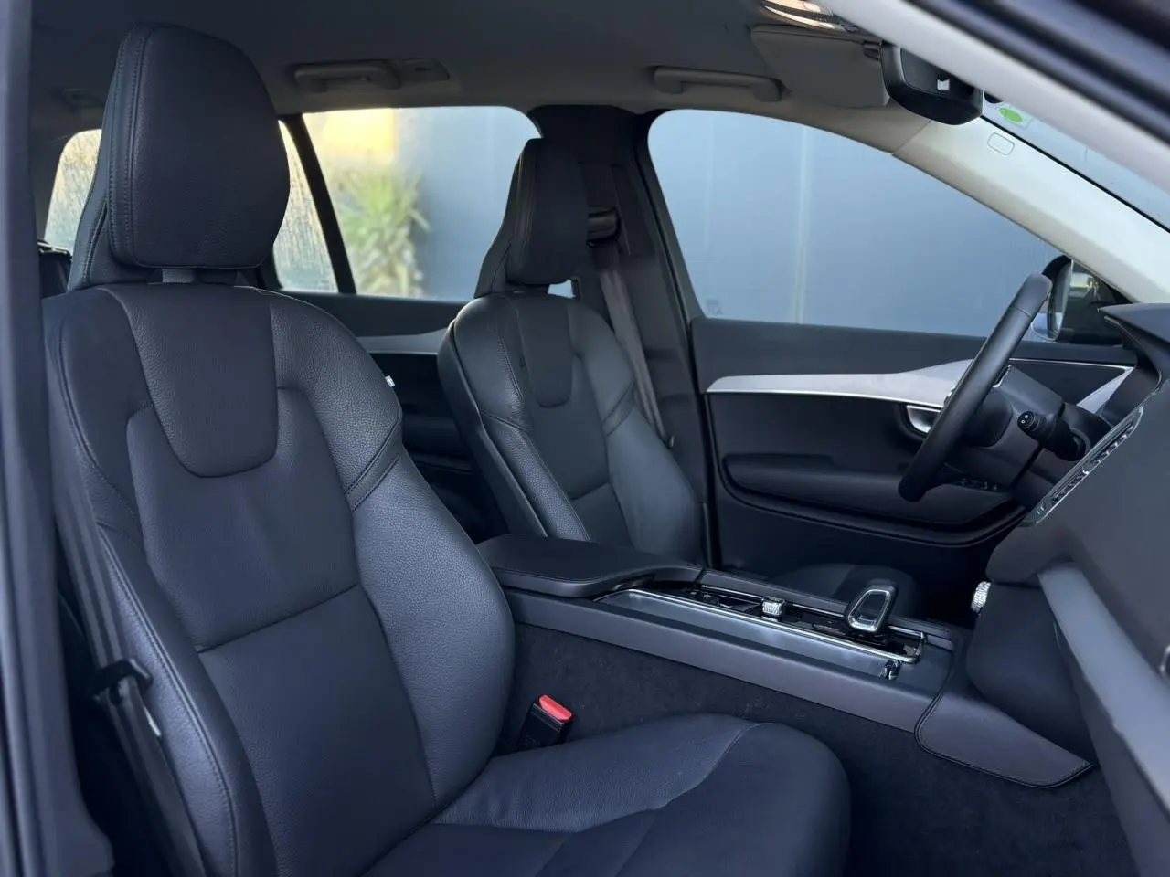 Intérieur du Volvo XC90 T8 2024 vu côté droit, sièges cuir noir et console centrale moderne avec accoudoir.