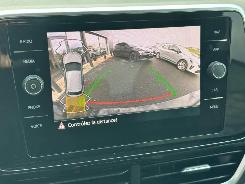 Vue caméra de recul du Volkswagen T-Roc gris 2025 en stationnement, avec assistance au freinage active visible.