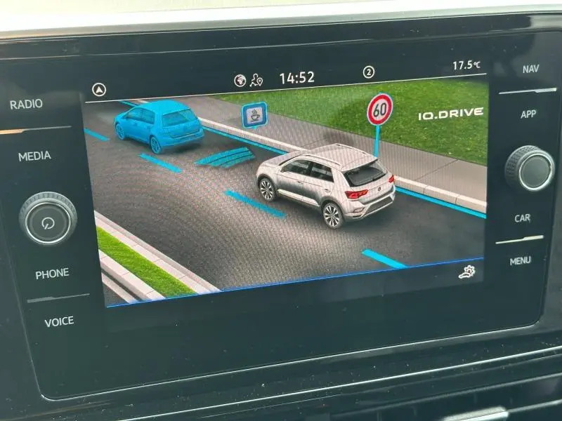 Affichage intérieur du système de conduite assistée montrant un Volkswagen T-Roc gris vu de trois quarts arrière sur écran tactile.