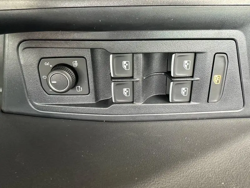 Commande des rétroviseurs et des vitres électriques sur la porte côté conducteur du Volkswagen T-Roc gris 2025 R-Line Edition.